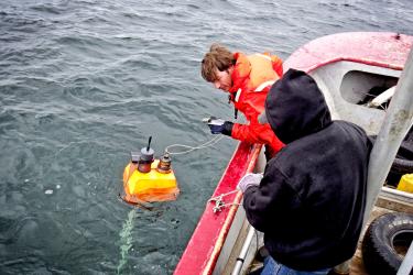 dam-migration-miss/1280_6QPFs5e1jdM5.jpg Two people stand on a boat and look out at a device on the water to conduct beluga whale acoustic monitoring.